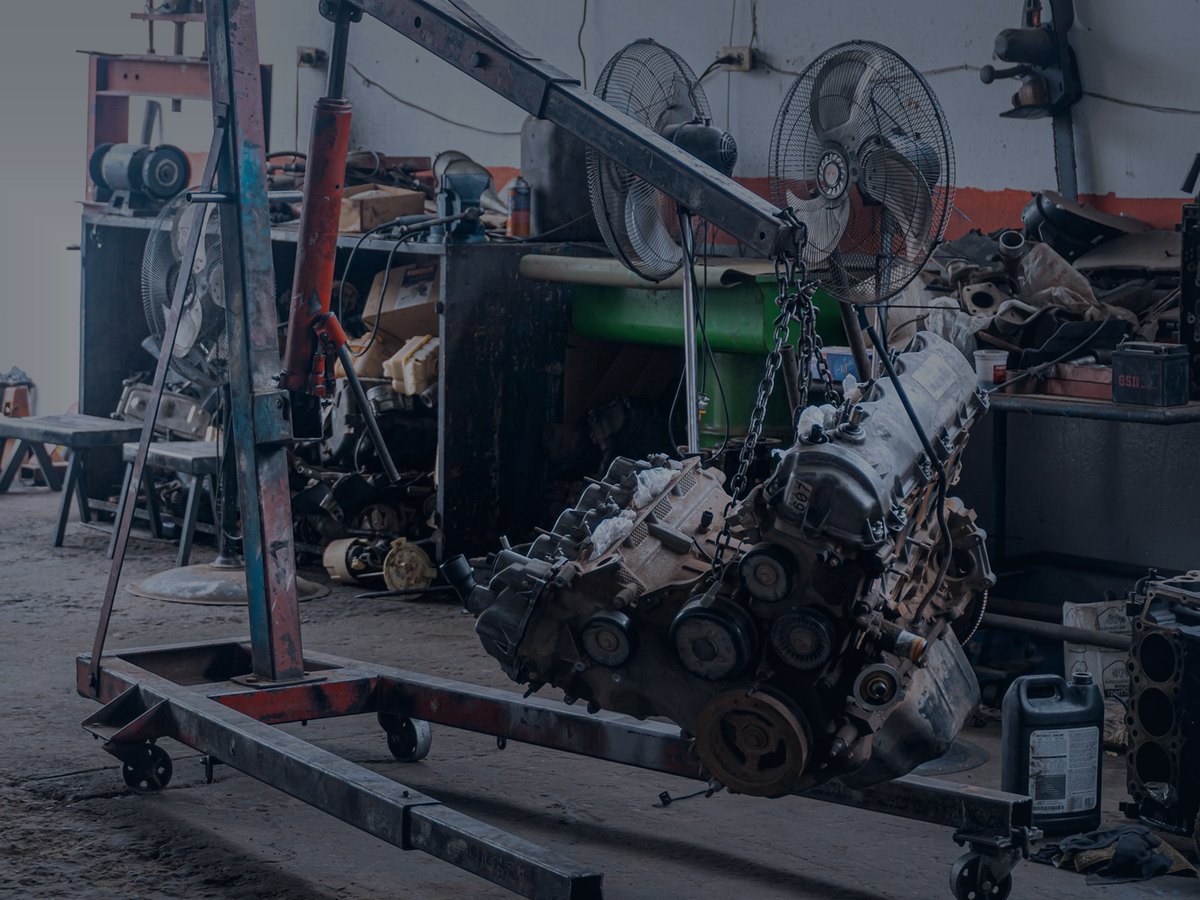 Vehicle engine hanging from a workshop engine crane