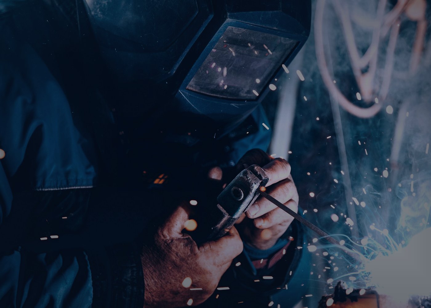 Close-up of a welder in a helmet striking an arc with sparks