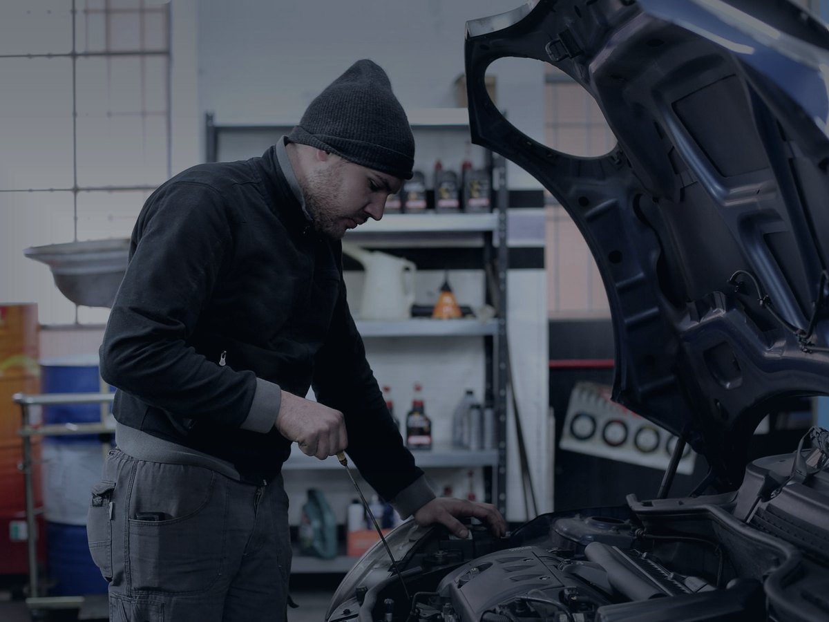 Mechanic checking the engine bay of a car in a workshop